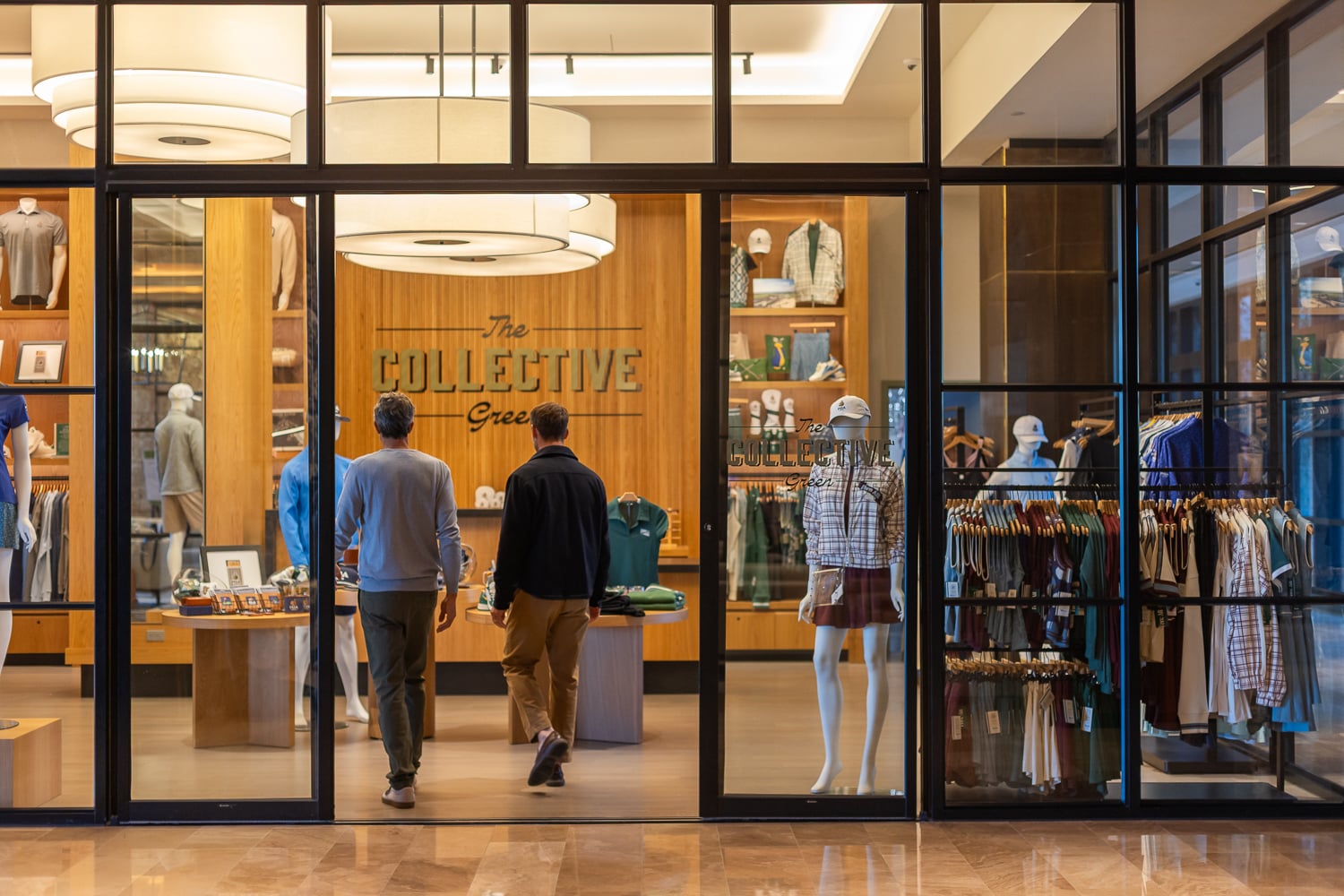 Two men walking through the glass entrance doors of 