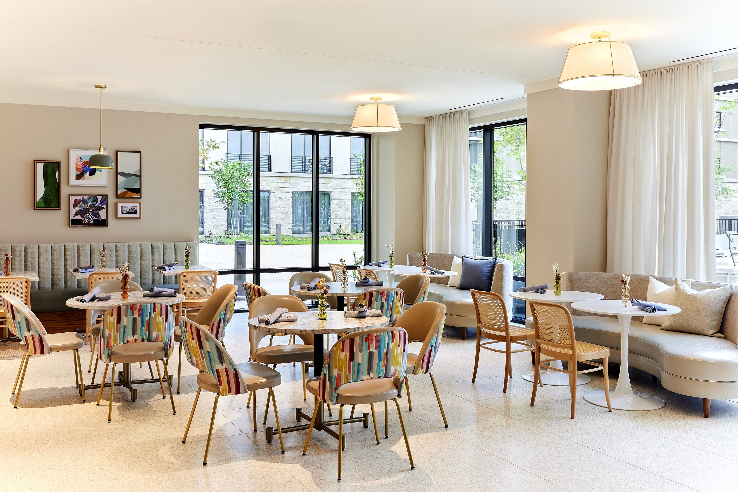 Bright interior of the Green Cactus Cafe & Spa, featuring colorful modern chairs, round tables, and neutral banquette seating.