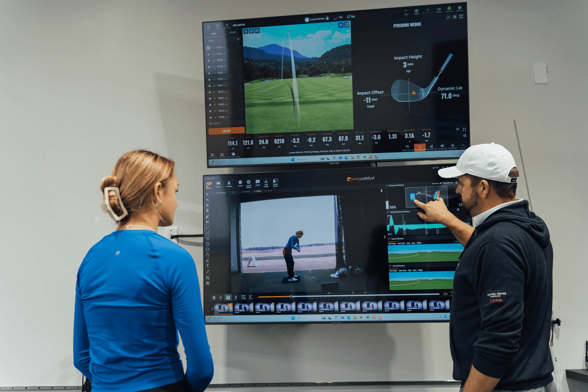 a golf instructor pointing to a screen displaying a students swing