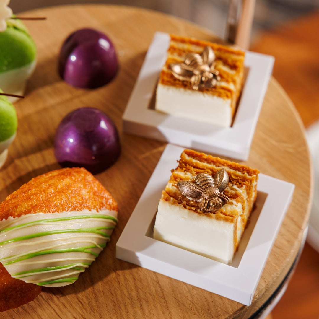 Close-up of elegant small desserts, including two square cakes with white frosting layers