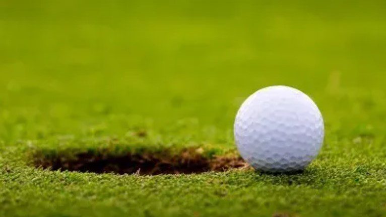 a golf ball about to roll into the cup