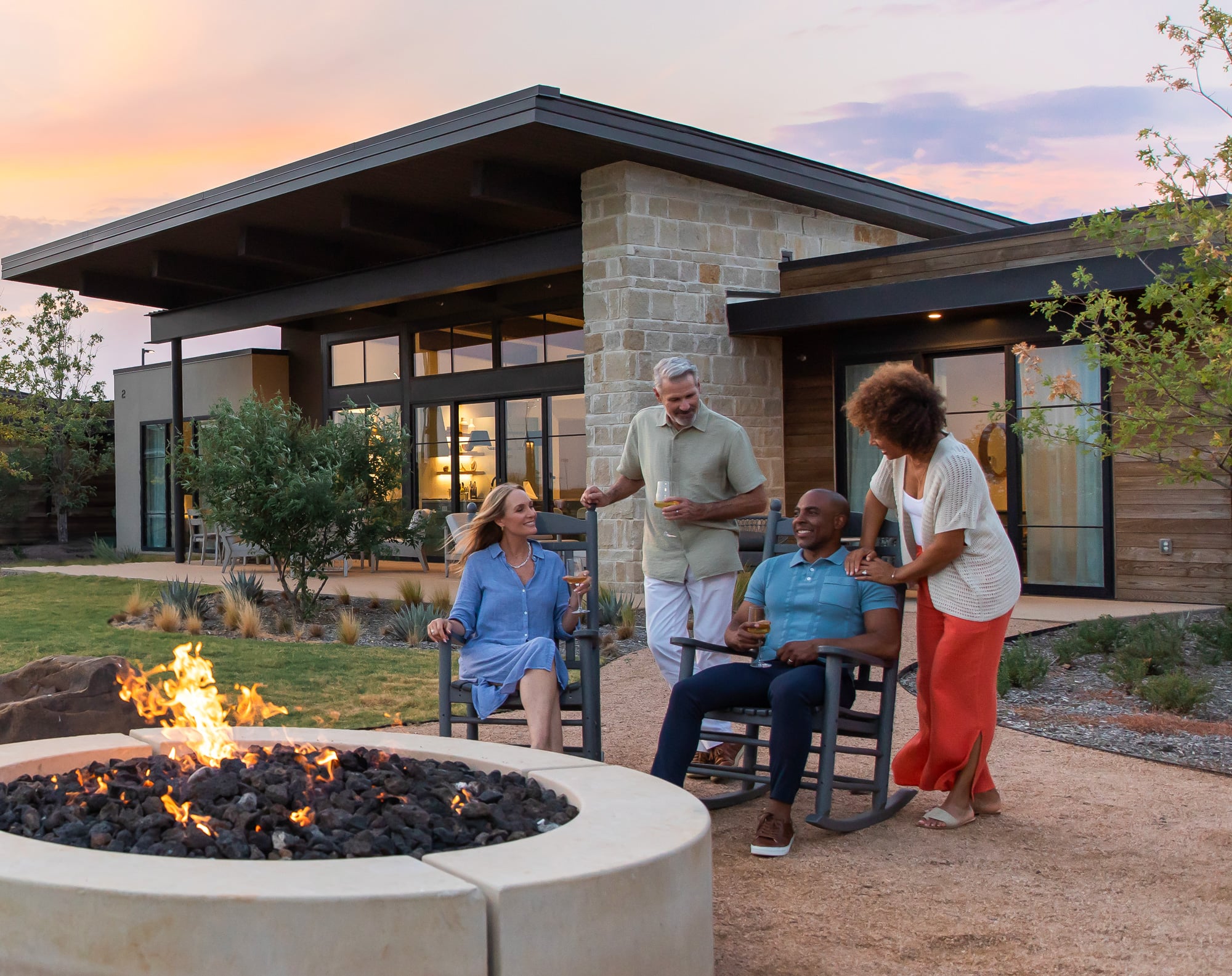 Two couples with drinks around fire pit