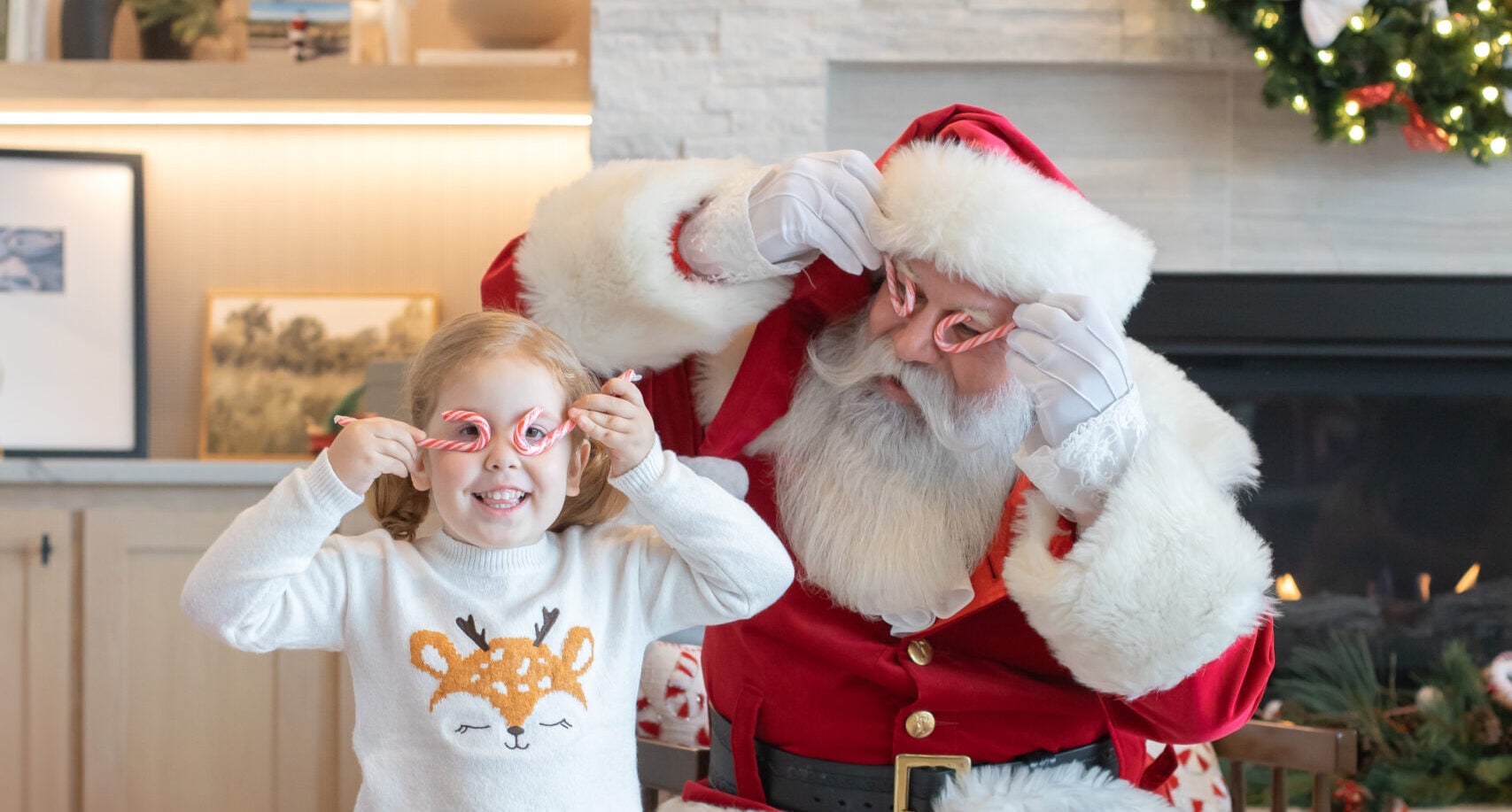 a photo with santa, holding candy canes in front of a holiday decorated room