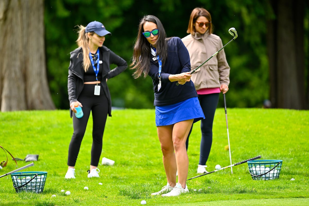 a woman chips a golf ball from the rough onto a green