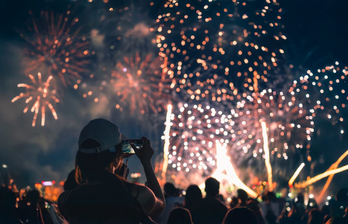 fireworks light up the sky as people take photos