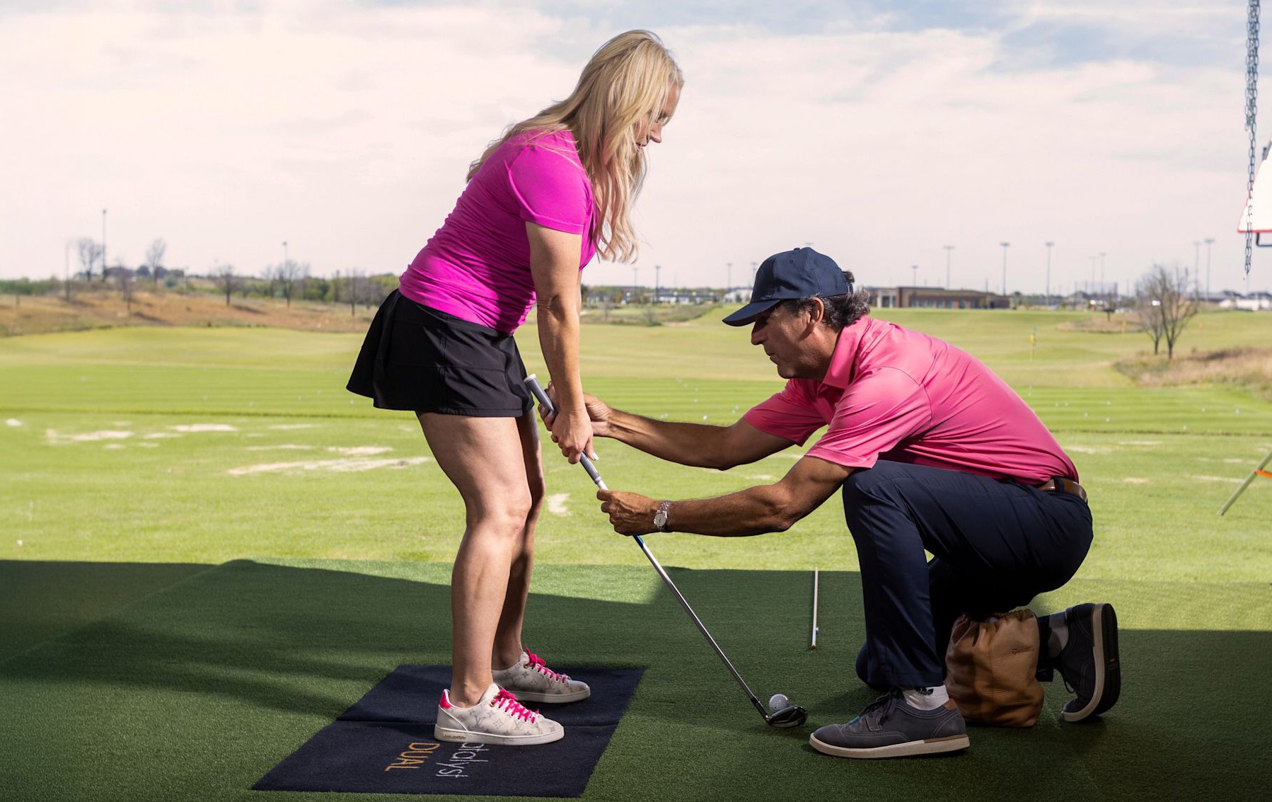 An instructor adjusting a student's club position during a lesson at the PGA Coaching Center.