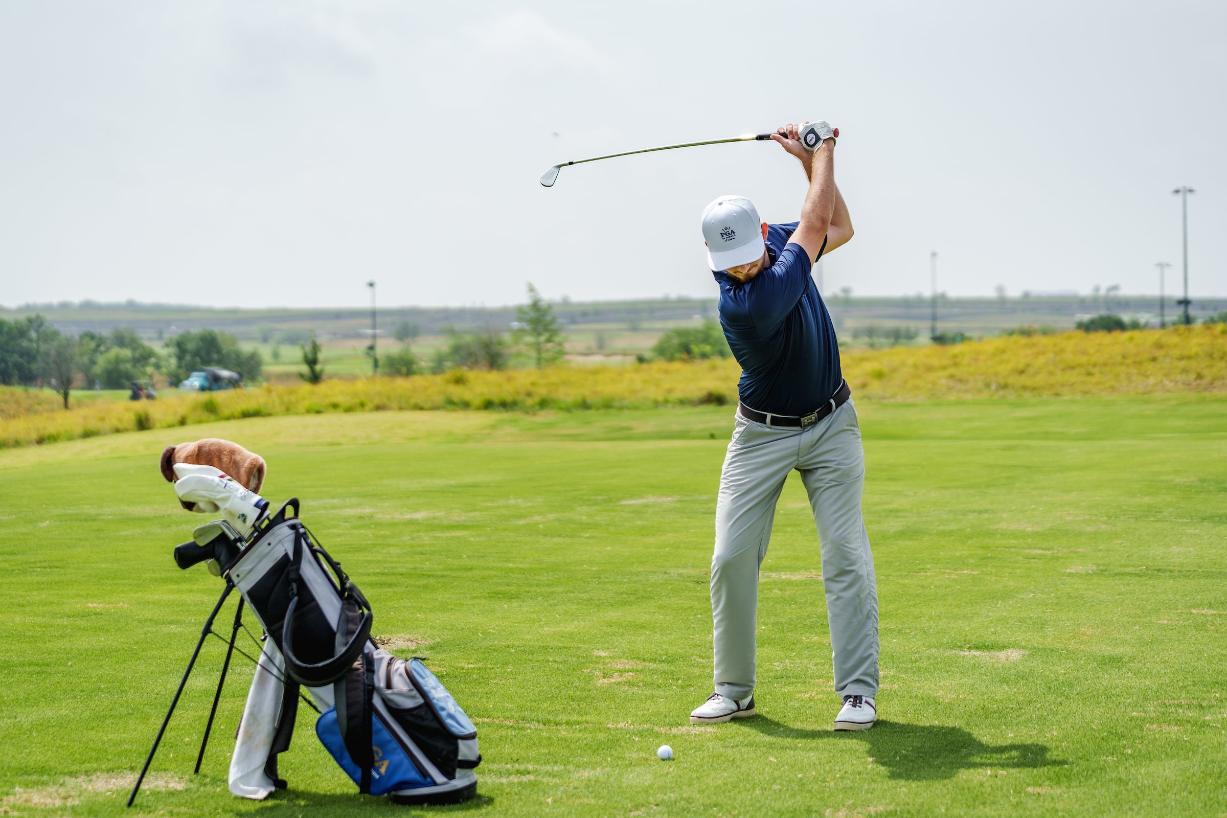 Man swinging a golf club at a ball with his golf bag in the shot