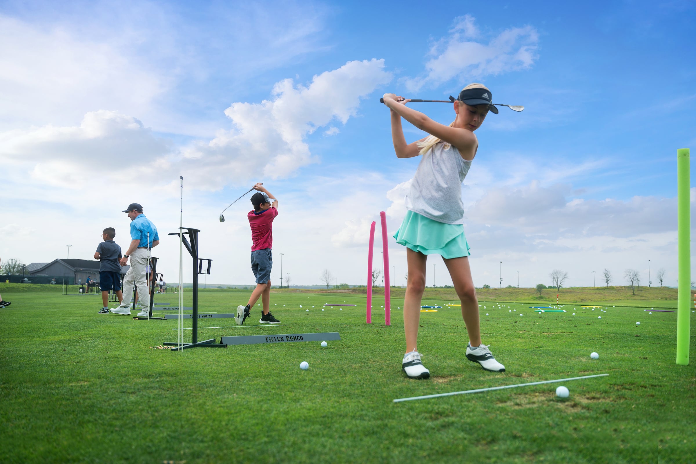 Children practicing their golf swing at a range