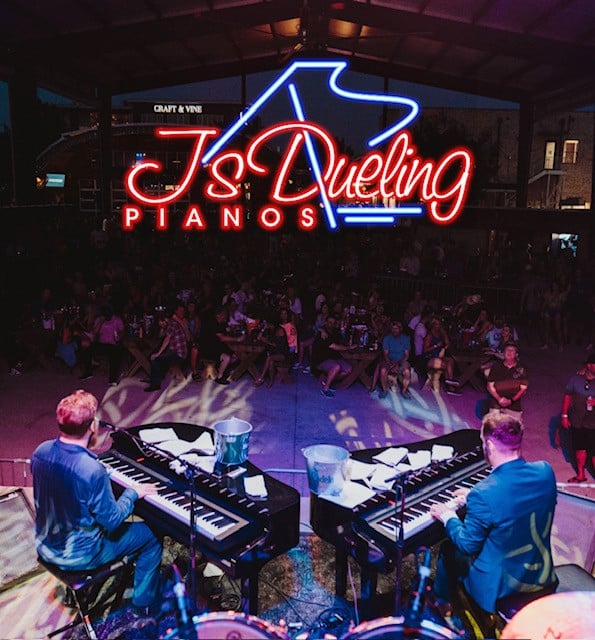 Two men playing pianos side by side